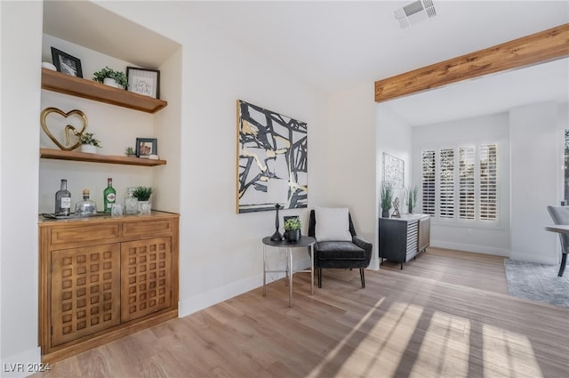 living area with beam ceiling and light hardwood / wood-style flooring