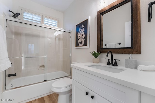 full bathroom featuring hardwood / wood-style floors, vanity, enclosed tub / shower combo, and toilet