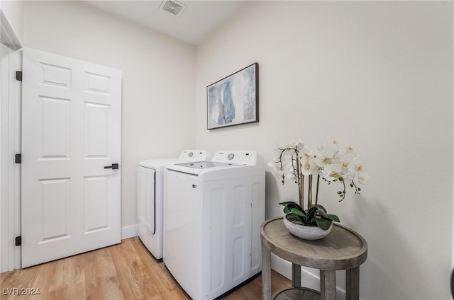 clothes washing area featuring washing machine and clothes dryer and light wood-type flooring