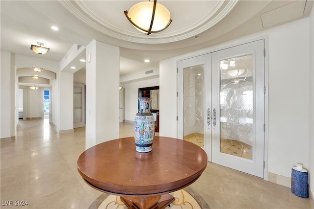 interior space with a tray ceiling, crown molding, and french doors