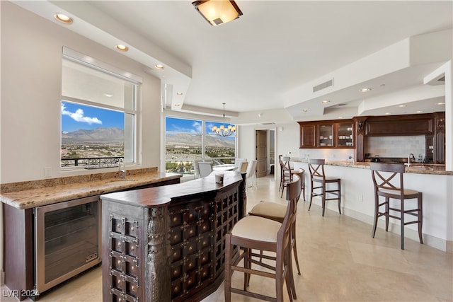 bar featuring backsplash, dark brown cabinetry, decorative light fixtures, an inviting chandelier, and wine cooler