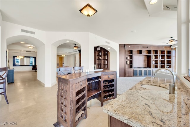 kitchen featuring light stone counters, built in features, and sink