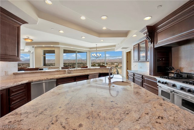 kitchen with decorative backsplash, sink, stainless steel appliances, and an inviting chandelier