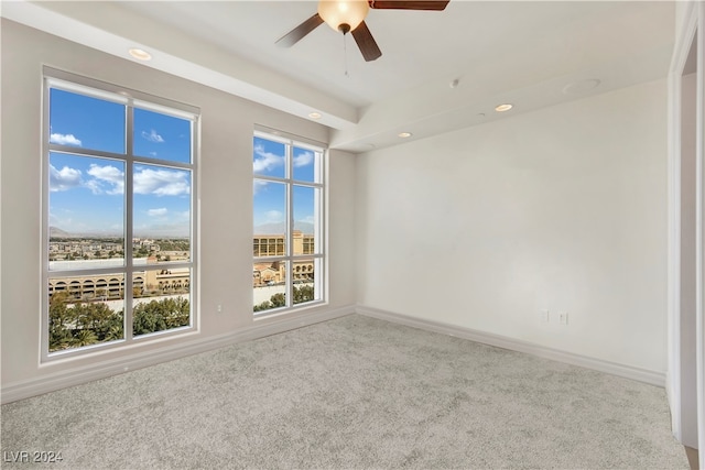 empty room with ceiling fan, a healthy amount of sunlight, and light colored carpet