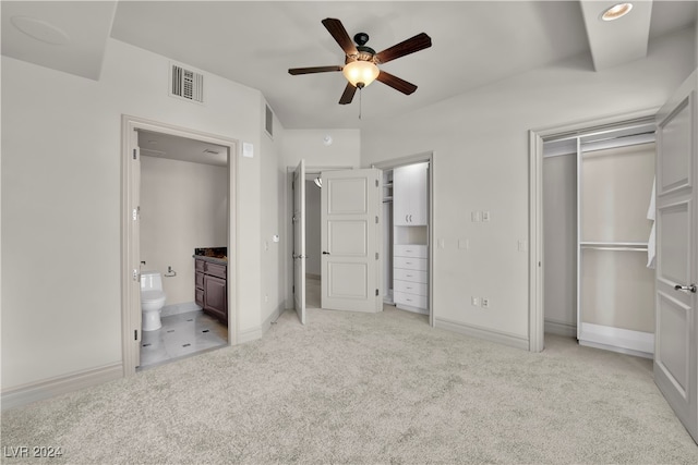 unfurnished bedroom with a closet, ceiling fan, ensuite bathroom, and light colored carpet