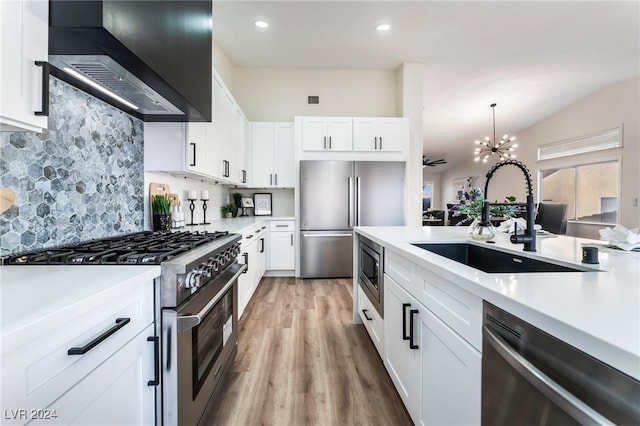 kitchen with high quality appliances, light hardwood / wood-style floors, white cabinetry, and wall chimney exhaust hood