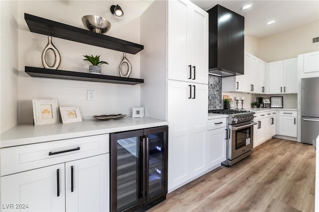 kitchen featuring white cabinets, wine cooler, light hardwood / wood-style flooring, wall chimney exhaust hood, and stainless steel appliances