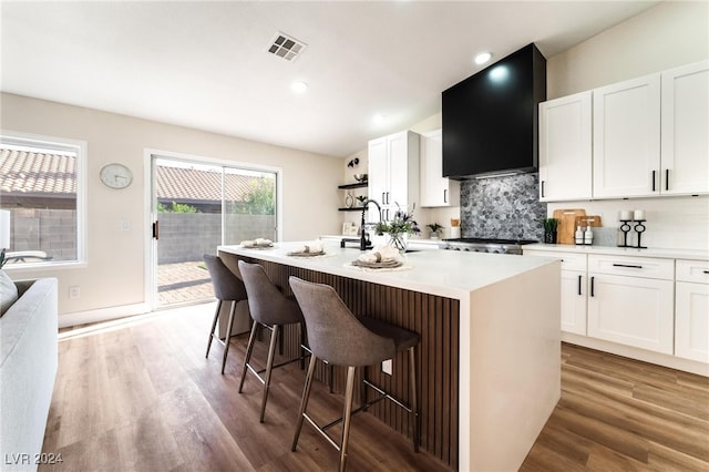 kitchen featuring a kitchen bar, white cabinetry, and an island with sink