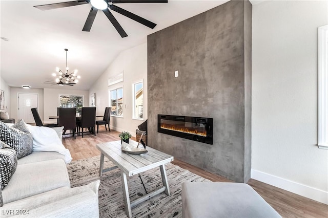 living room with hardwood / wood-style flooring, ceiling fan with notable chandelier, lofted ceiling, and a fireplace