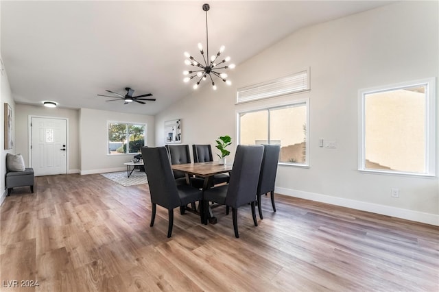 dining room with ceiling fan with notable chandelier, light wood-type flooring, and lofted ceiling