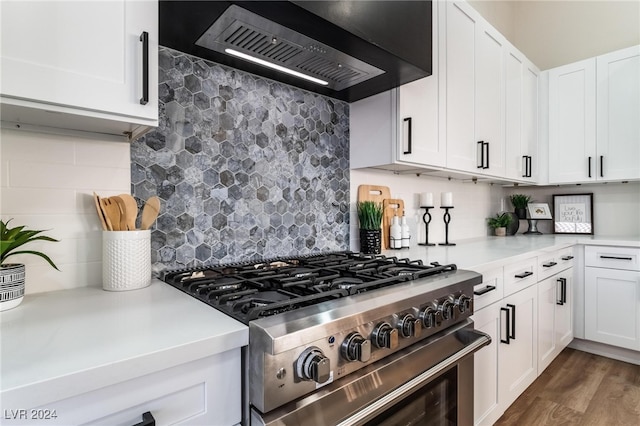 kitchen featuring high end range, decorative backsplash, white cabinetry, and wall chimney exhaust hood