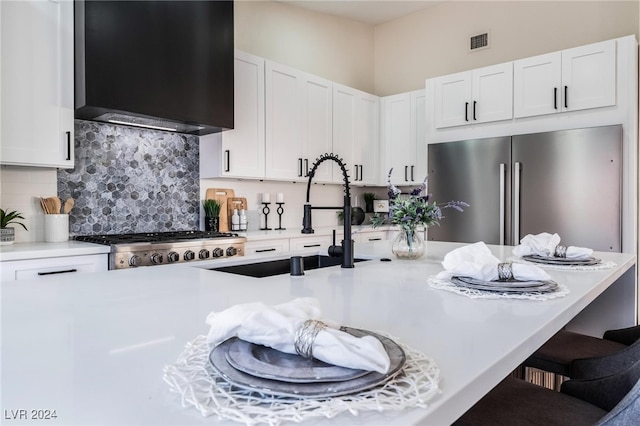 kitchen featuring decorative backsplash, wall chimney exhaust hood, stainless steel appliances, sink, and white cabinets