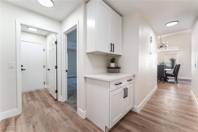 hall with light hardwood / wood-style floors and a notable chandelier