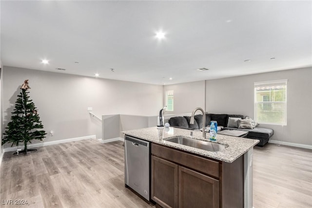 kitchen with light wood-style flooring, stainless steel dishwasher, open floor plan, a sink, and an island with sink