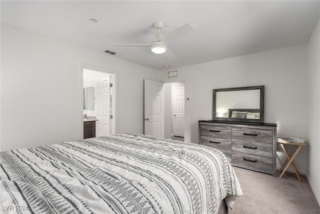 bedroom featuring visible vents, ensuite bathroom, baseboards, light colored carpet, and ceiling fan