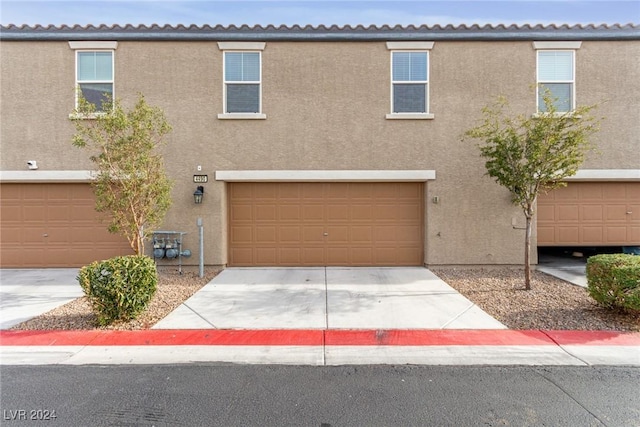 view of property with stucco siding, a garage, and concrete driveway