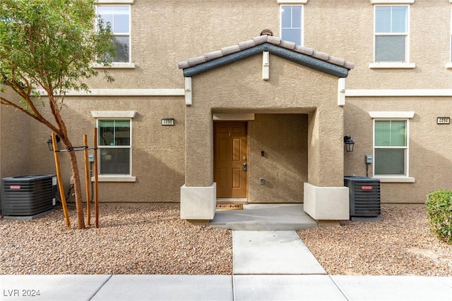 property entrance featuring central AC, a tile roof, and stucco siding