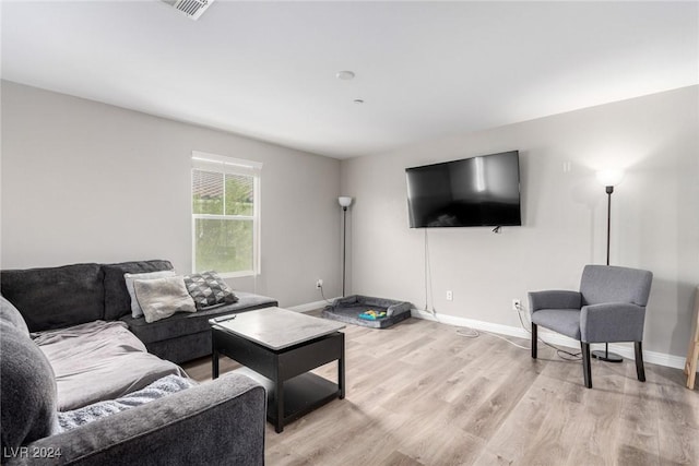 living area with light wood-type flooring, visible vents, and baseboards