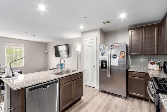 kitchen featuring dark brown cabinetry, visible vents, appliances with stainless steel finishes, a kitchen island with sink, and a sink