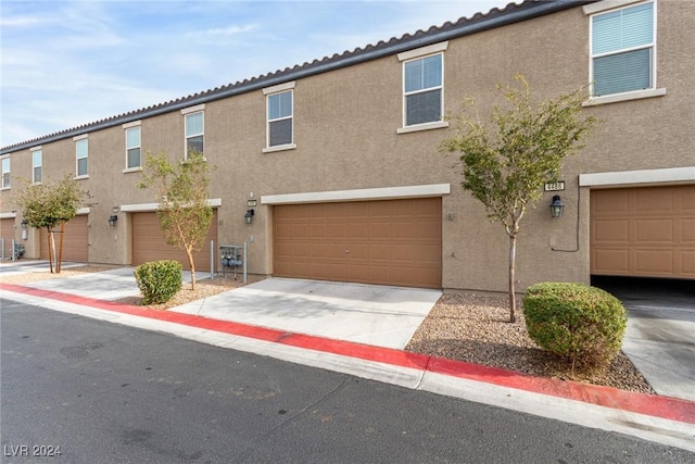 townhome / multi-family property featuring concrete driveway, an attached garage, and stucco siding