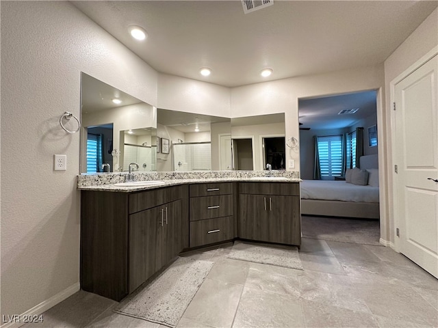 bathroom featuring double vanity, visible vents, a stall shower, a sink, and baseboards