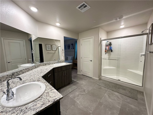 full bathroom with double vanity, a shower stall, visible vents, and a sink