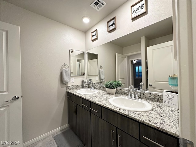 full bathroom with double vanity, a sink, visible vents, and baseboards