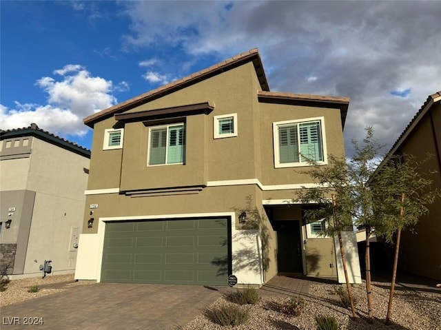 view of front of house featuring an attached garage, decorative driveway, and stucco siding