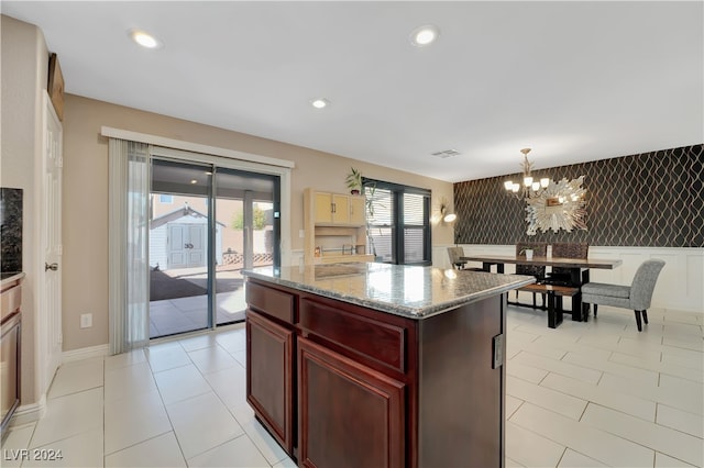 kitchen featuring a center island, an inviting chandelier, hanging light fixtures, light stone countertops, and light tile patterned floors