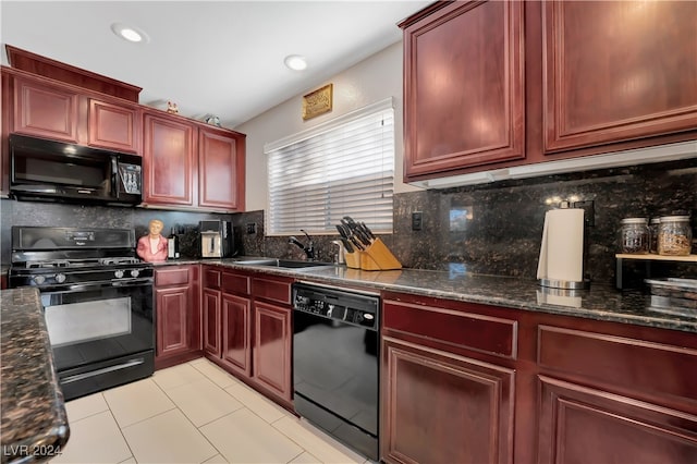 kitchen with sink, dark stone counters, decorative backsplash, light tile patterned floors, and black appliances