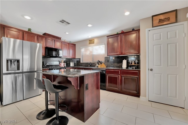 kitchen featuring decorative backsplash, dark stone counters, sink, black appliances, and a kitchen island