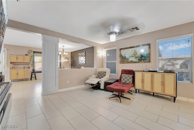 sitting room with light tile patterned flooring and ceiling fan with notable chandelier