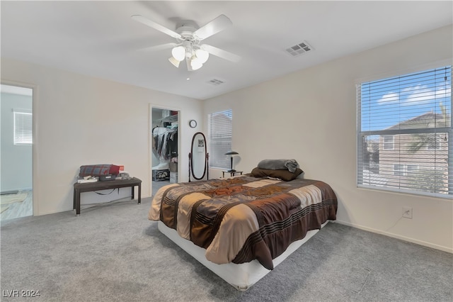 bedroom featuring ceiling fan, a spacious closet, light carpet, and multiple windows