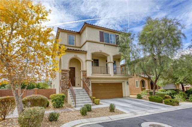 mediterranean / spanish home featuring stucco siding, driveway, a tile roof, a garage, and a balcony