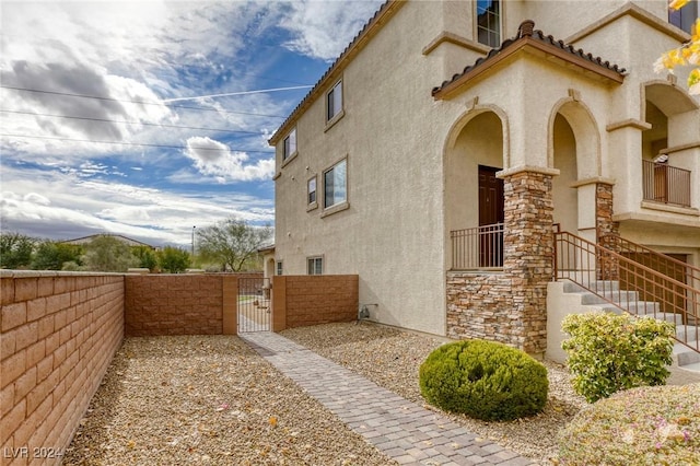 view of home's exterior with a tiled roof, stucco siding, fence, and a gate