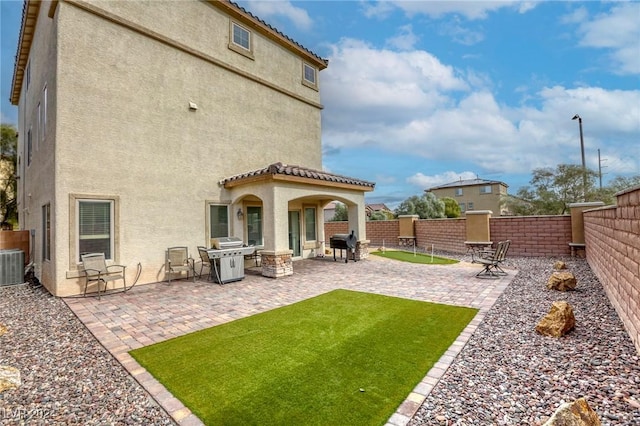 rear view of house with a patio, a fenced backyard, a tile roof, and stucco siding