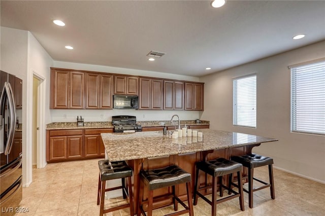 kitchen featuring visible vents, recessed lighting, appliances with stainless steel finishes, a breakfast bar area, and light stone countertops