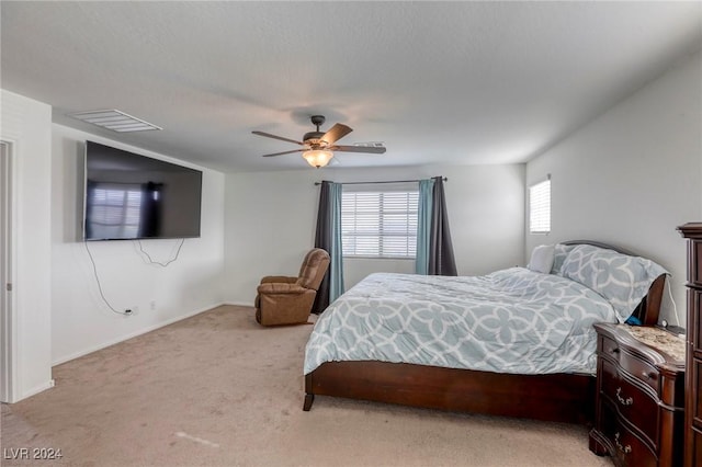 bedroom featuring visible vents, light colored carpet, baseboards, and a ceiling fan