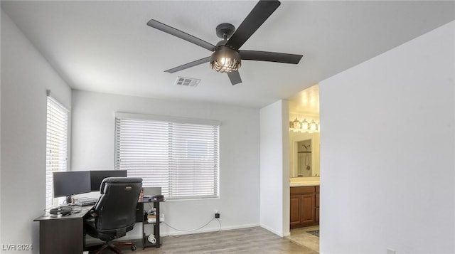 home office featuring visible vents, baseboards, ceiling fan, and light wood finished floors