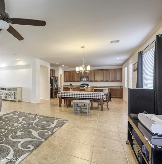 dining room with light tile patterned flooring and ceiling fan with notable chandelier