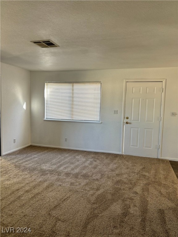 carpeted spare room featuring a textured ceiling