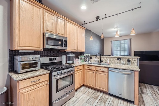 kitchen featuring pendant lighting, sink, kitchen peninsula, and stainless steel appliances