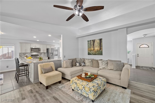 living room with ceiling fan, light hardwood / wood-style flooring, and sink