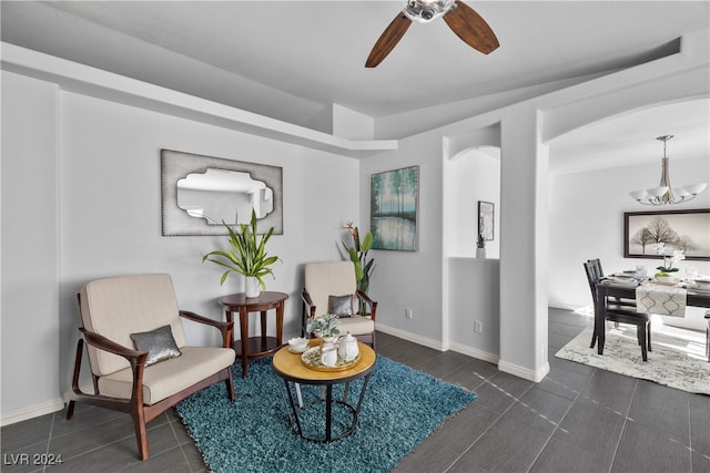 living area featuring ceiling fan with notable chandelier