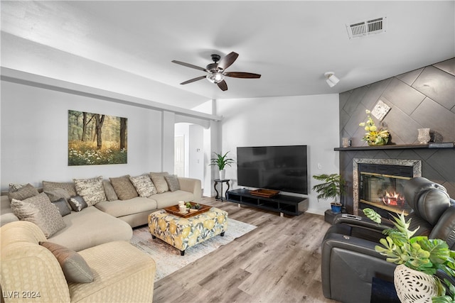 living room with a premium fireplace, hardwood / wood-style floors, ceiling fan, and vaulted ceiling