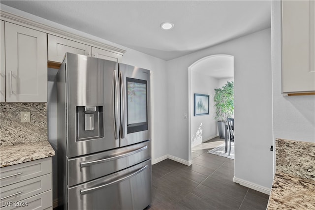 kitchen featuring light stone countertops, stainless steel fridge, tasteful backsplash, gray cabinetry, and dark tile patterned floors