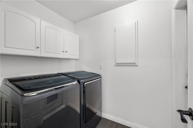 washroom featuring washing machine and dryer, dark hardwood / wood-style flooring, and cabinets