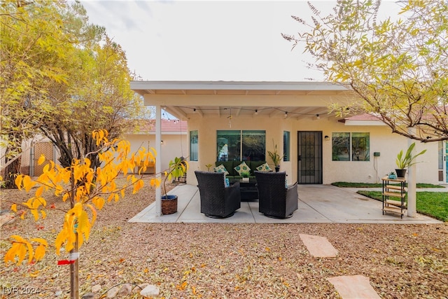 back of property with an outdoor living space and a patio