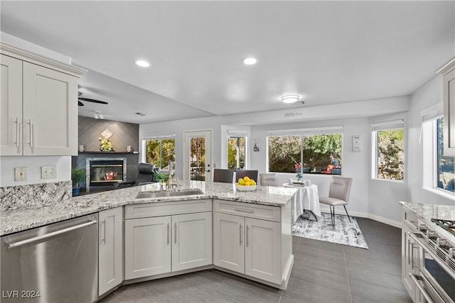 kitchen with dishwasher, light stone counters, plenty of natural light, and sink