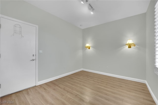 spare room featuring track lighting and light hardwood / wood-style flooring